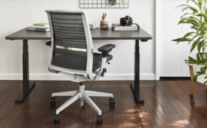 steelcase desk in a home office with white wall and dark flooring with steelcase chair